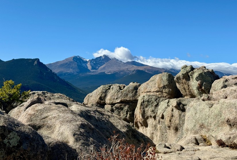 A panoramic view of mountains and rocky outcrops under a clear blue sky, showcasing the rugged terrain and natural beauty of the area.