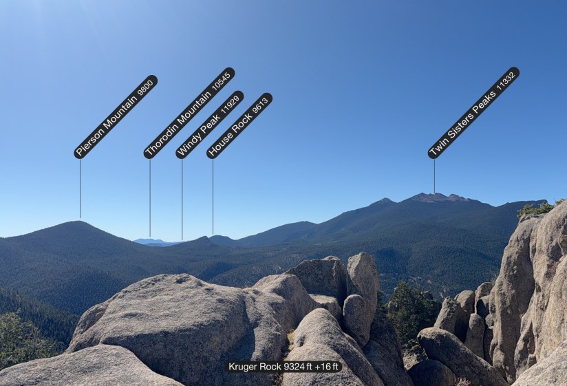 Panoramic view from Kruger Rock showing multiple mountain peaks labeled with their elevations, including Pierson Mountain, Thorodin Mountain, Windy Peak, House Rock, and Twin Sisters Peaks.