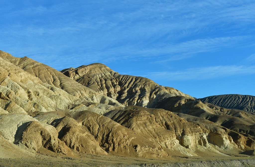 Rocky mountain landscape with layered hills and blue sky.