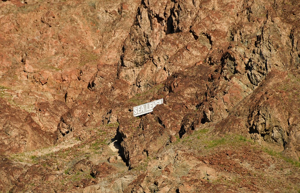 A rocky landscape with a prominent sign that says 'SEA LEVEL' positioned among the boulders.