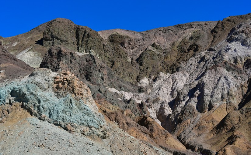Colorful rocky mountains with various mineral hues under a clear blue sky.