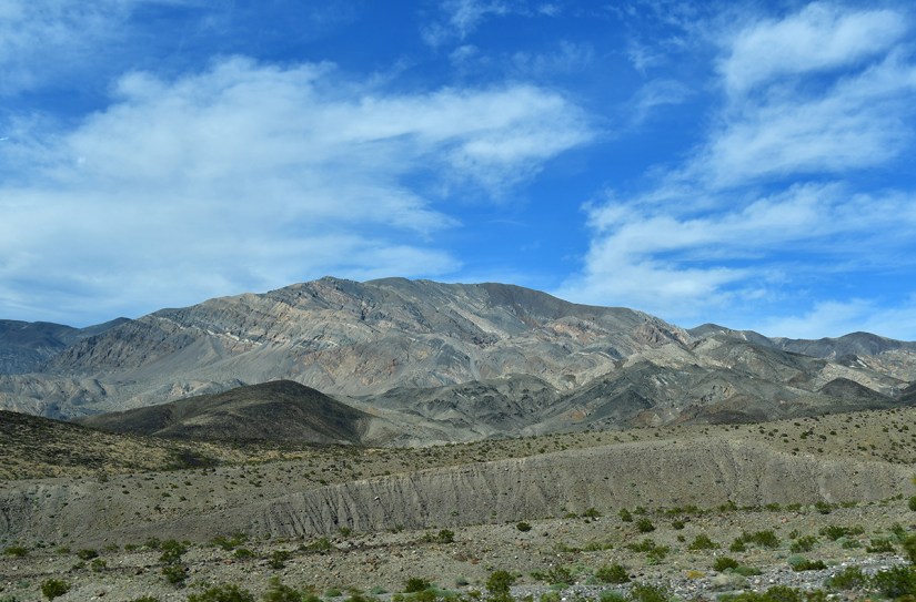 Mountain landscape with rocky terrain under a blue sky with scattered clouds.