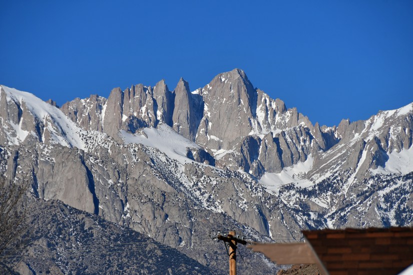 Snow-capped mountains under a clear blue sky, showcasing rugged peaks and rocky terrain.