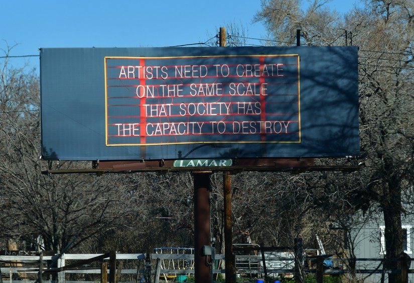 Billboard displaying the message: 'Artists need to create on the same scale that society has the capacity to destroy.'