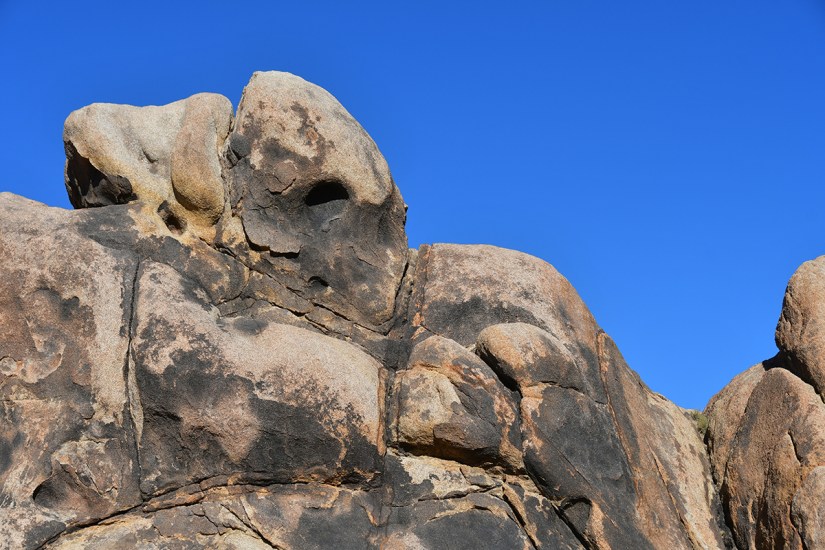 Close-up view of a textured rock formation against a clear blue sky.