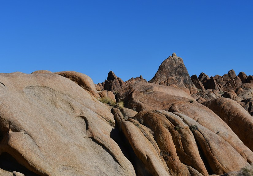 Rocky landscape featuring large, smooth boulders under a clear blue sky.