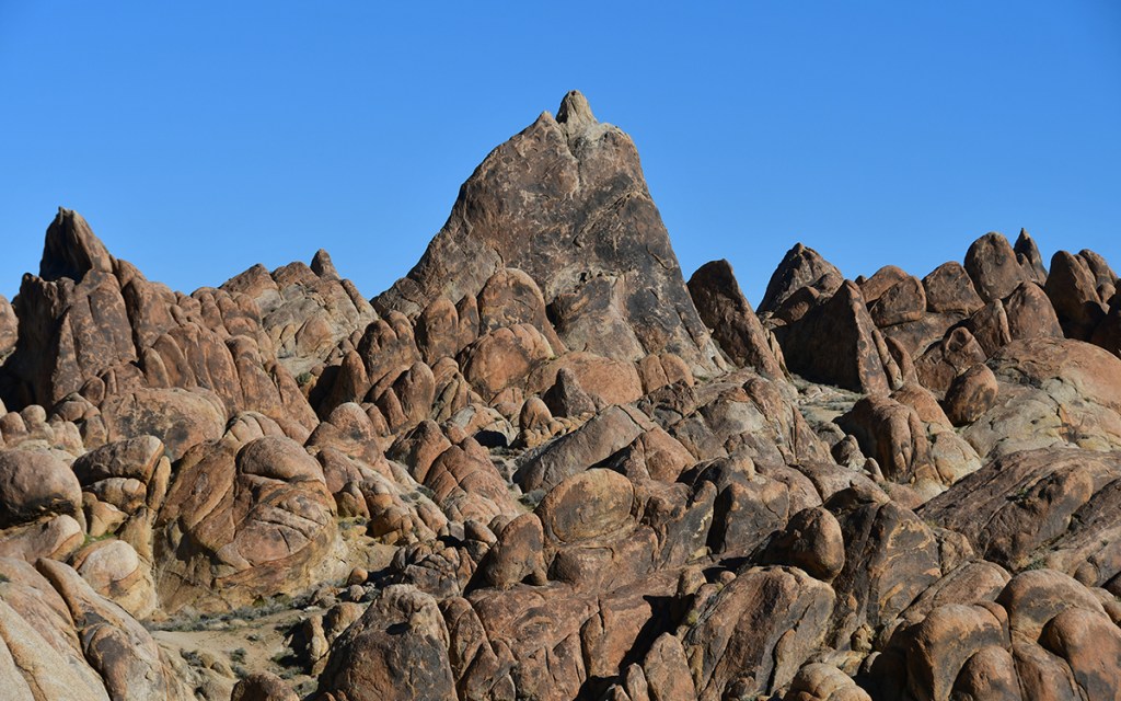 A rugged landscape of large, weathered rock formations under a clear blue sky.