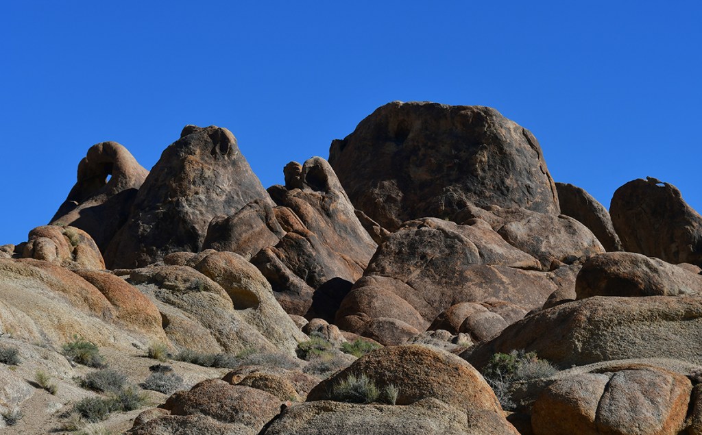 Rock formations under a clear blue sky, showcasing various shapes and textures.