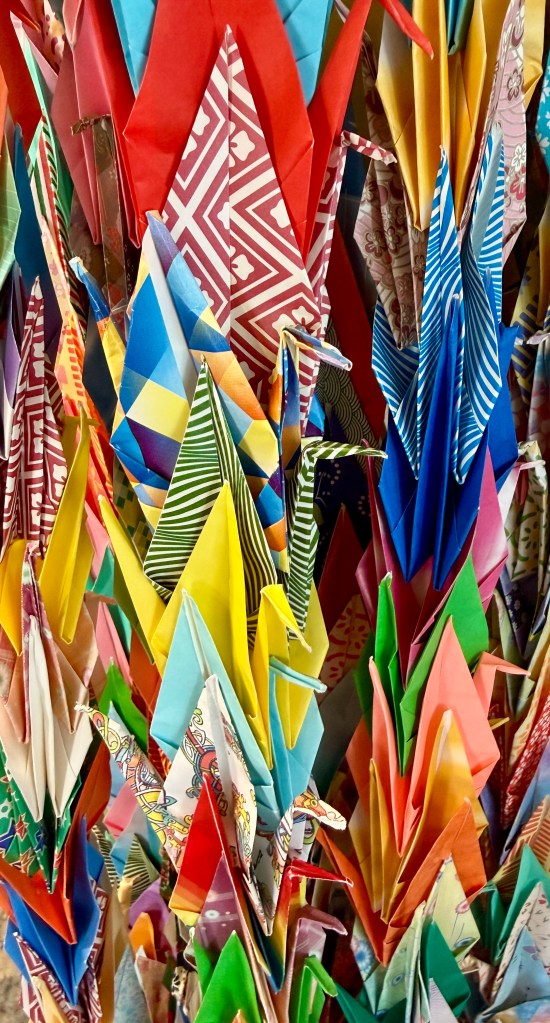A vibrant collection of colorful origami cranes displayed together, showcasing a variety of patterns and colors.