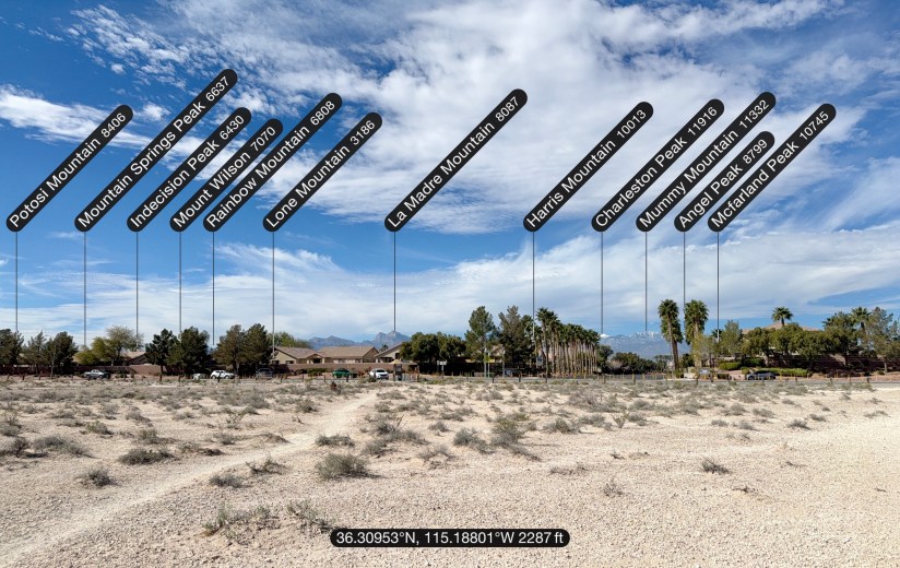Panoramic view of several mountains with name labels and elevations, set against a clear blue sky and a desert landscape.
