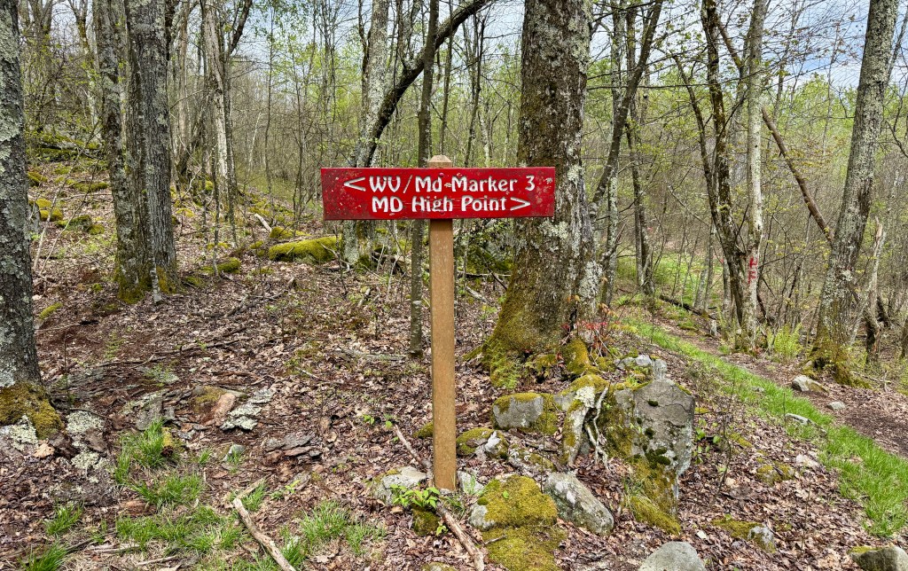 Trail sign indicating '< WU/Md-Marker 3' and 'MD High Point' surrounded by trees and rocky terrain.