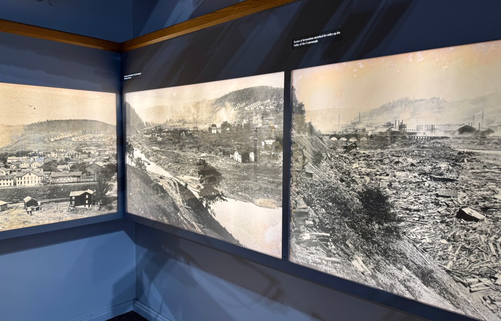 Three historical photographs displayed on a wall, depicting a valley with buildings and landscape signs of industrialization.