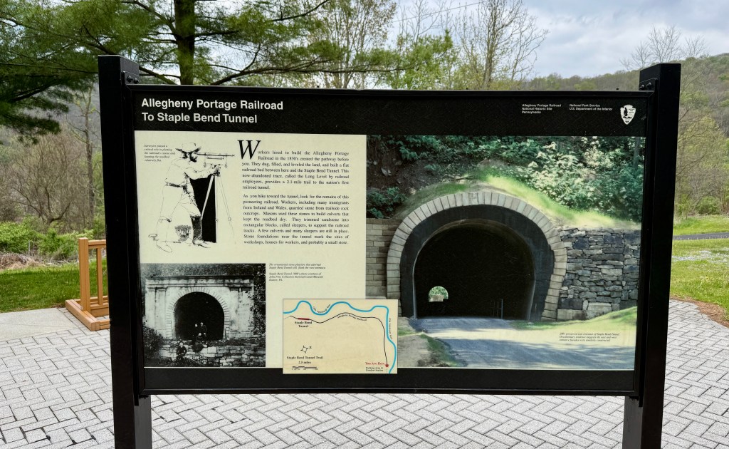 Informational sign for the Allegheny Portage Railroad, featuring details about the Staple Bend Tunnel, historical illustrations, and a map.