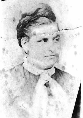 Black and white portrait of a woman with a bun hairstyle, wearing a blouse with a tie collar.