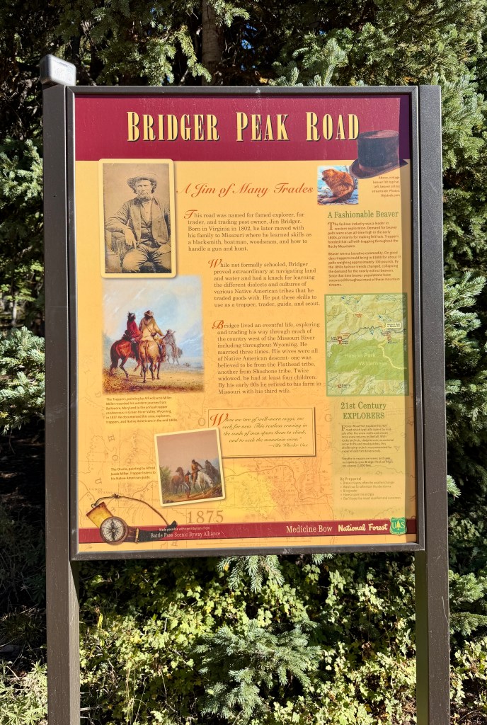 Historical sign for Bridger Peak Road detailing the life of explorer Jim Bridger, featuring images and text about his trades and experiences.