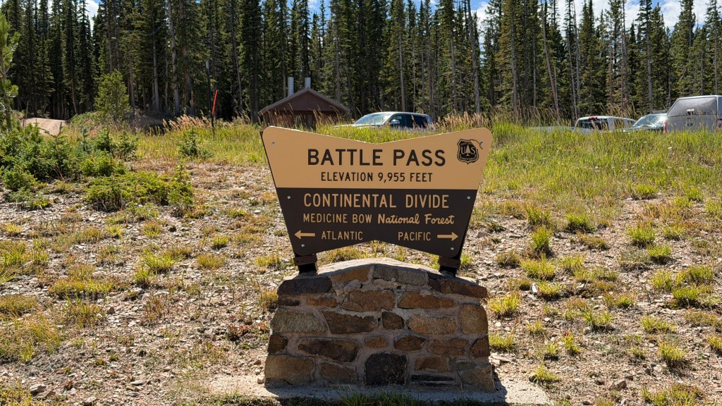 Sign for Battle Pass at an elevation of 9,955 feet, indicating the Continental Divide and Medicine Bow National Forest, with directional arrows for Atlantic and Pacific.